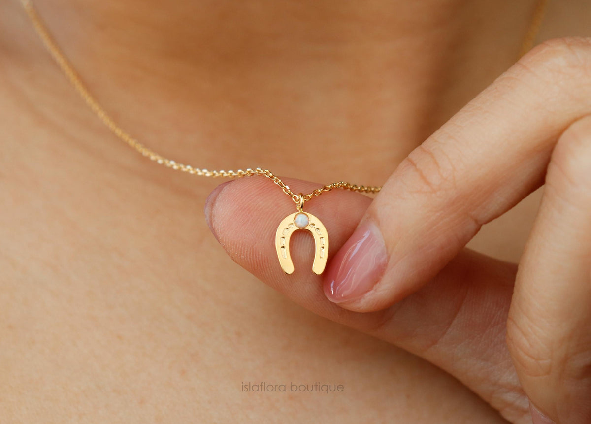 Gold necklace with a horseshoe pendant on a person's neck
